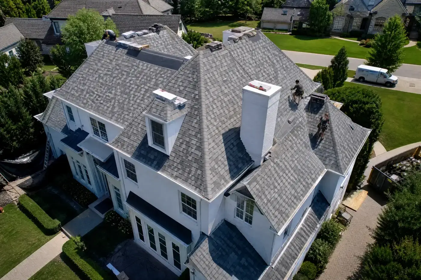 A street-level view highlights a red brick Masonic center with a clean white gabled roofline, showcasing a property perfectly maintained by professional roofing services.