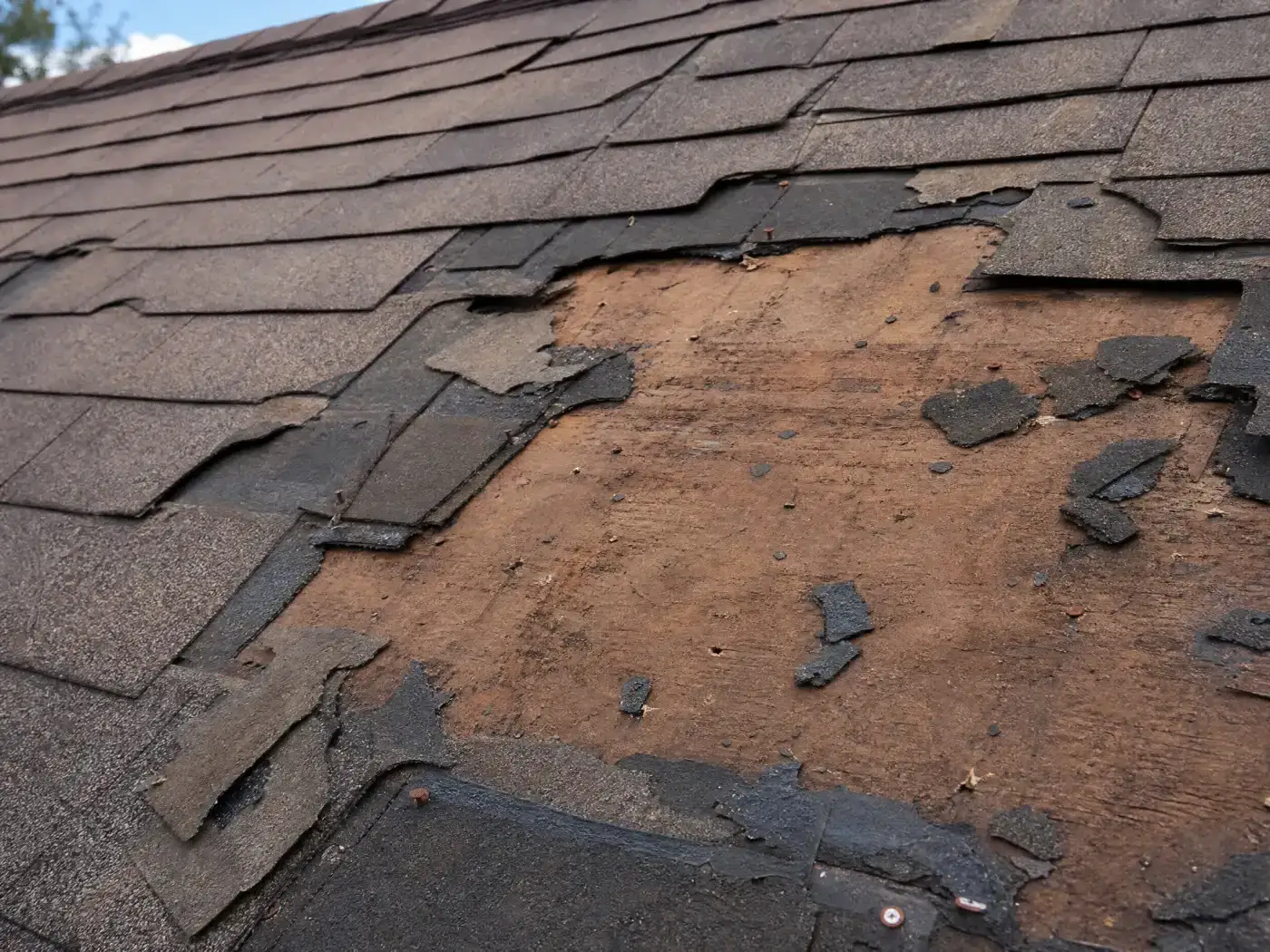 An aerial view highlights a multi-story residential home with a large wrap-around porch and a newly completed dark asphalt shingle roof installed by a skilled roofing contractor.